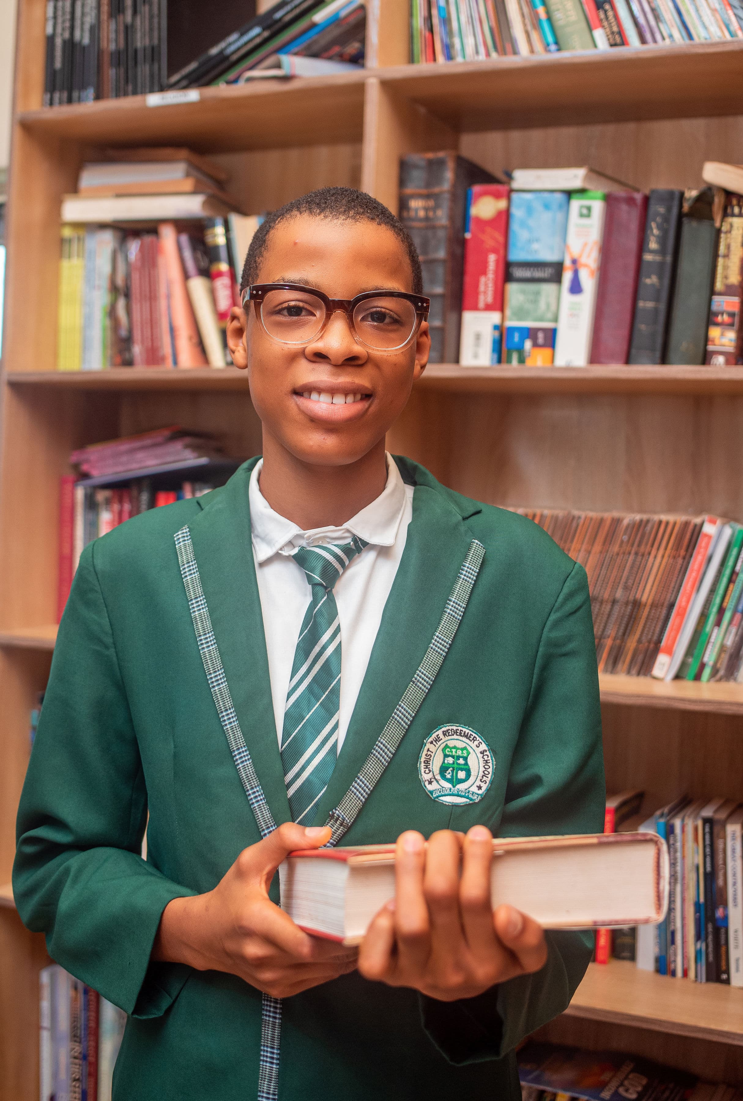 Secondary student in CTRS uniform holding a book in the library